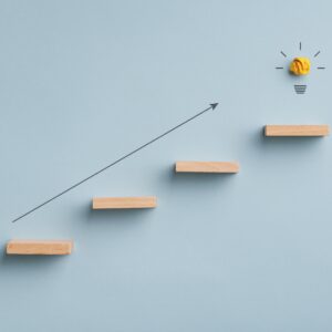 Βέλος που δείχνει προς τα πάνω και σκάλα με λαμπτήρα στο επάνω μέρος. Εικόνα που επιδιώκει να προβάλλει τις έννοιες της καινοτομίας και της φιλοδοξίας