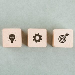 Τρεις ξύλινοι κύβοι που δίχνου εικονίδια σχετικά με την επίτευξη στόχου